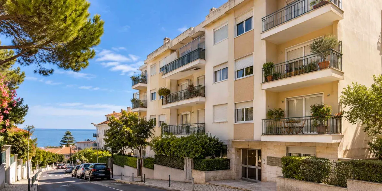 Prédio residencial usado, com varandas e fachada bege, numa rua de São João do Estoril, ilustrando a venda de imóveis com usufruto ou nua-propriedade em Cascais.